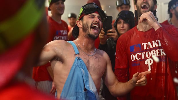 Garrett Stubbs yells while wearing overalls soaked in champagne